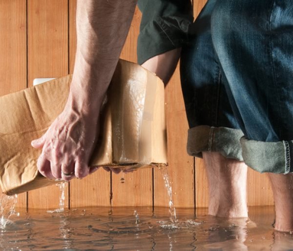 Man lifting cardboard box in flooded basement, low section